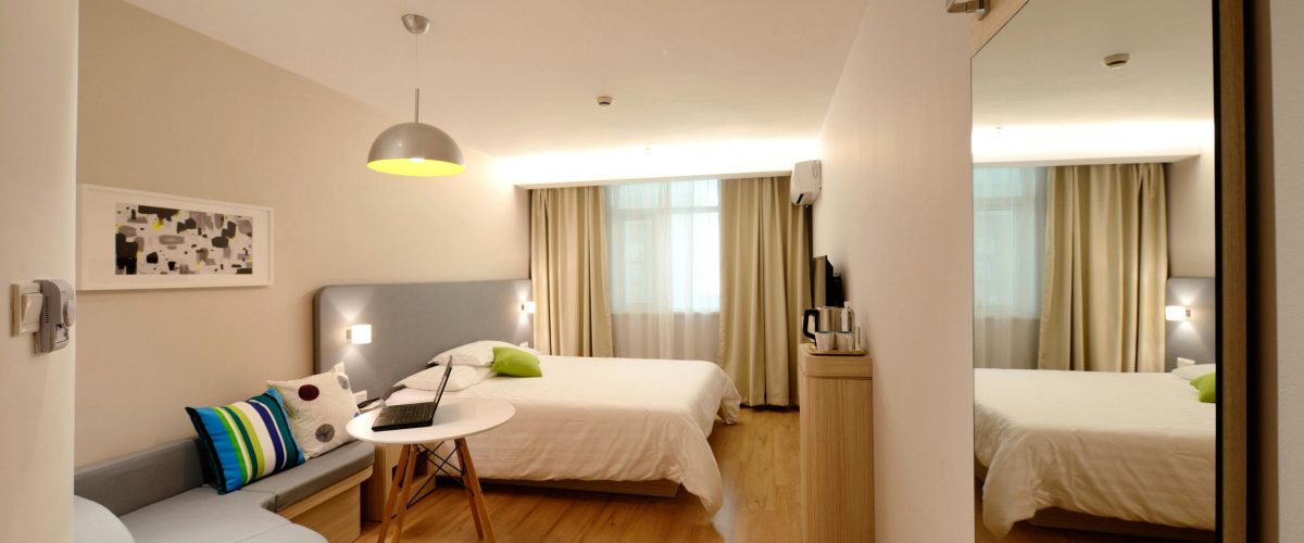 Spacious modern hotel room featuring cozy decor and neutral tones with natural light.